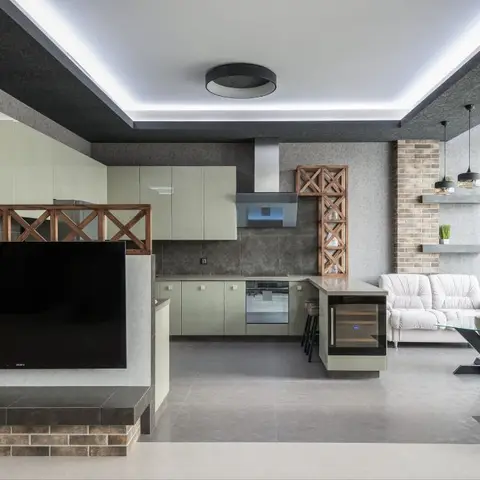 Open-plan kitchen and living space with sage glossy cabinetry, a waterfall-edge island with built-in wine cooler