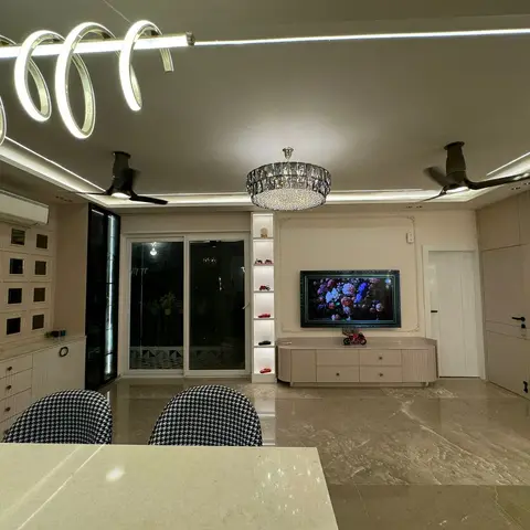 Open-plan kitchen-counter foreground opening into a living area with a sculptural spiral LED ceiling feature, marble flooring and a floating TV console.
