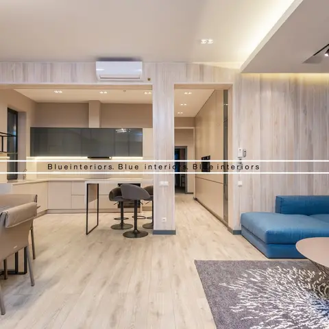 Open-plan kitchen, dining and living area with vertical wood-slat wall panelling and a blue sectional sofa