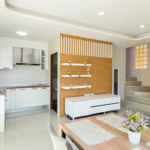 Open-plan kitchen, dining and stair landing with a mustard textured accent wall and white gloss kitchen cabinetry.