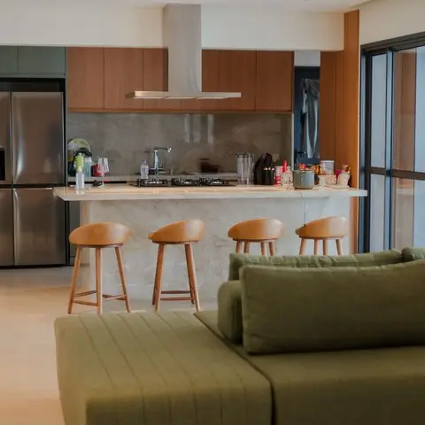 Open-plan kitchen island with wooden overhead cabinets and a steel chimney hood, four counter stools