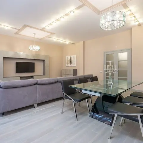 Open-plan living and dining area with a stone-clad TV wall, a grey sectional sofa