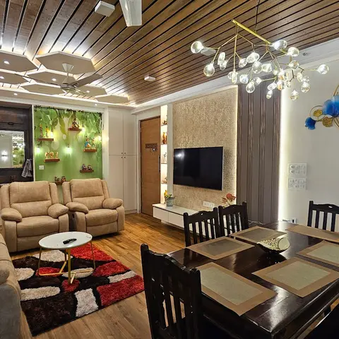 Open-plan living and dining area with a sculptural hexagon-panel false ceiling over the sofa zone, a wood-slat ceiling over the dining table