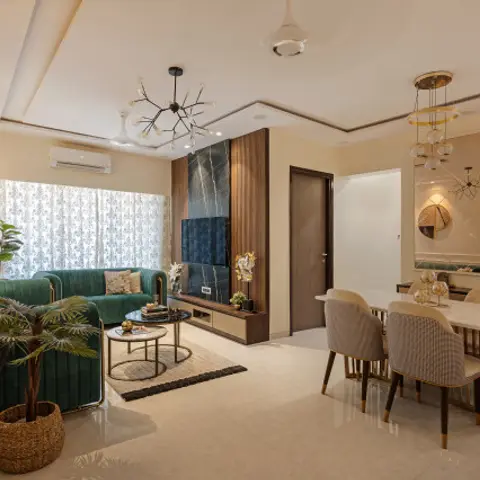 Open-plan living and dining space with a green velvet sofa facing a marble-and-wood TV wall under a sputnik chandelier
