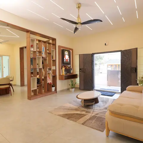 Open-plan living and dining space divided by a wood display shelf and a small wall altar, under a linear-striped false ceiling