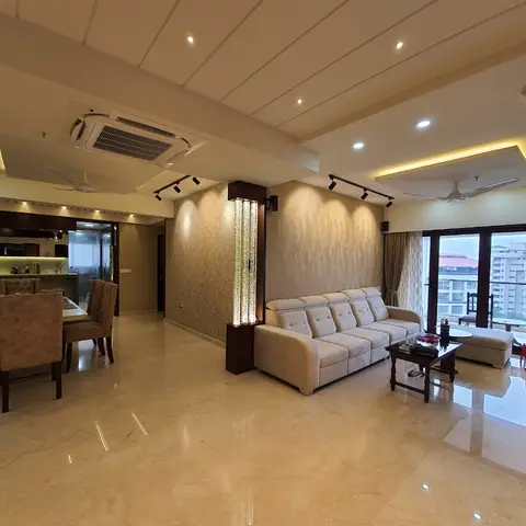 Open-plan living and dining space with cream marble flooring, a cove-lit stepped ceiling, a beige sofa set by floor-to-ceiling windows