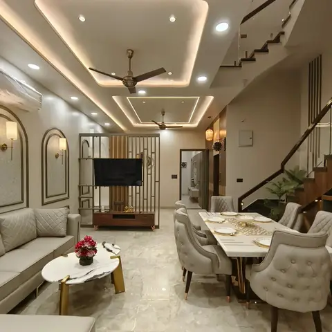 Open-plan living and dining space with a layered cove-lit POP ceiling, a metal jaali TV divider, a marble dining table with grey tufted chairs