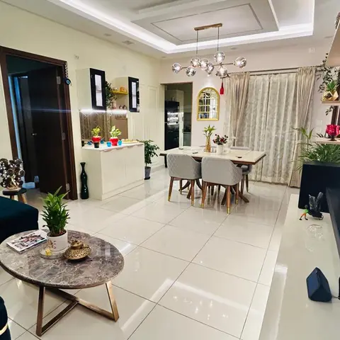 Open-plan living and dining space with a teal velvet sofa, a marble-top coffee table, and a dining table lit by a multi-globe sputnik chandelier.