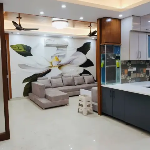 Open-plan living and kitchen area with a large hand-painted floral wall mural behind a grey sectional sofa