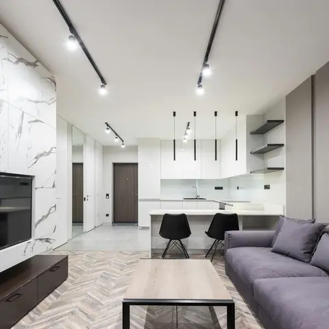 Open-plan living and kitchen with a marble-slab clad TV wall, herringbone wood flooring