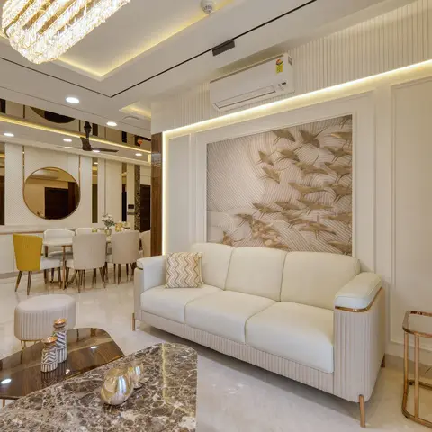 Open-plan living area with a cream leather sofa beneath a carved bronze bird-motif wall panel, crystal chandeliers, a marble coffee table with rose-gold legs
