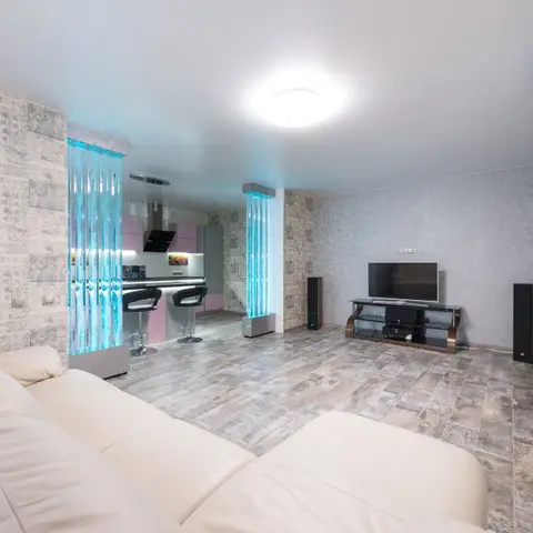 Open-plan living area with patterned grey wallpaper walls, illuminated blue glass floor-to-ceiling columns