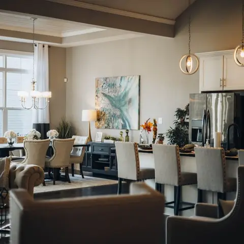 Open-plan living, dining and kitchen island viewed together with upholstered dining chairs, a chandelier and glass pendant lights over the island