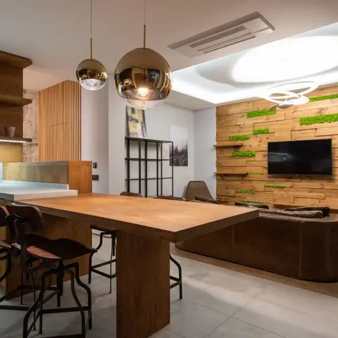 Open-plan living-dining-kitchen with a moss-inlaid wood slat TV wall, a curved leather sofa, gold globe pendant lights over a wood dining table