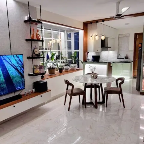 Open-plan living-dining-kitchen with a floating TV console, a round marble-top dining table, pendant lights over the kitchen pass