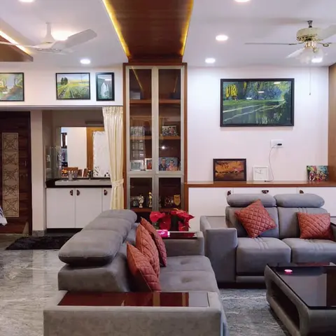 Open-plan living-dining space with a wood dining table on the left, grey tufted sofas facing a black coffee table