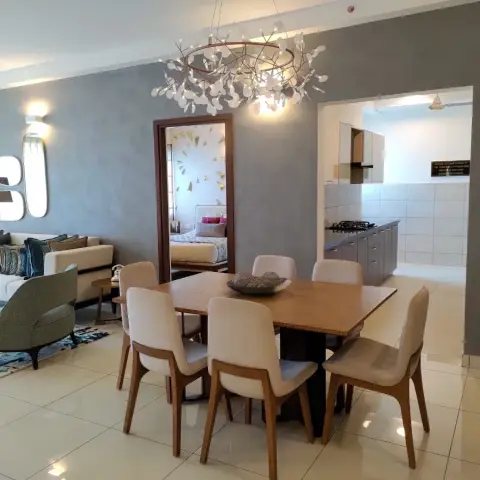 Open-plan living-dining space with a branch-style pendant chandelier over a wooden dining table, a mirror cluster on a textured grey wall