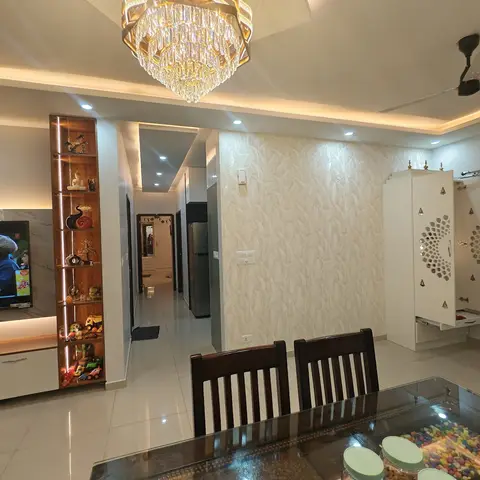 Open-plan living-dining space with a wood display shelf beside the TV unit, a dining table in the foreground
