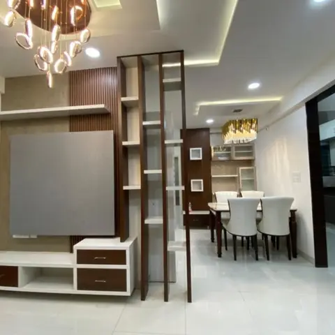 Open-plan living-dining space with a fluted-wood TV feature wall, a sculptural pendant chandelier, and a wood-and-glass crockery unit beside the dining table