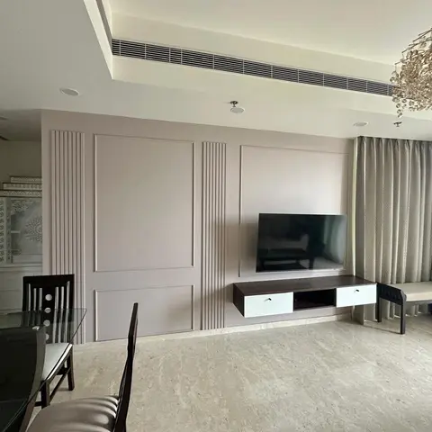 Open-plan living-dining space with a fluted-panel TV feature wall, floating console and a crystal cluster chandelier over a glass dining table on marble
