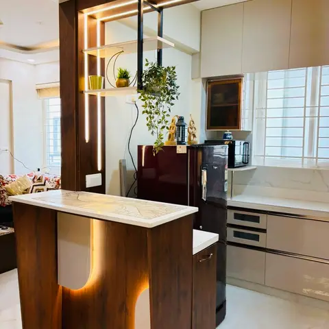 Open-plan living-kitchen with a backlit walnut partition breakfast counter, floating display shelf, and a cream glossy modular kitchen beyond.
