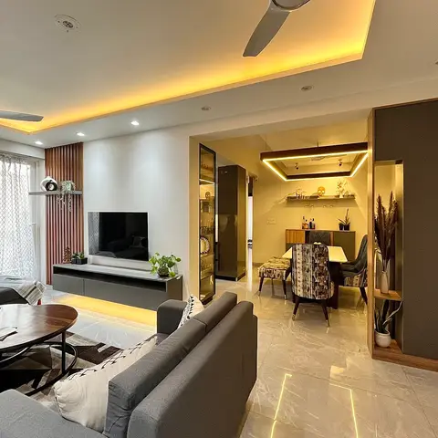 Open-plan living room with a wood-slat accent wall beside a floating grey TV console under a warm cove-lit ceiling