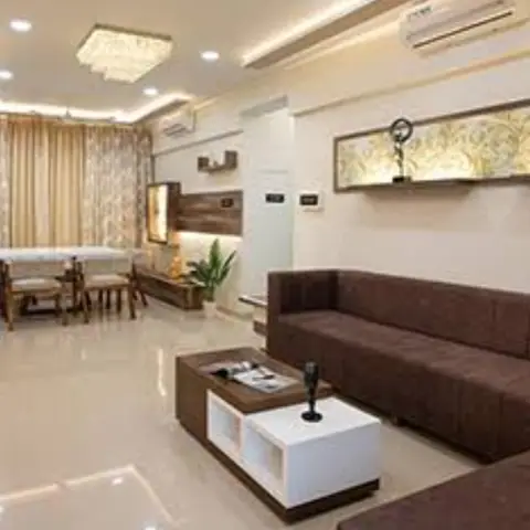 Open-plan living room with a multi-tier cove-lit ceiling, a crystal pendant chandelier, a backlit gold floral-motif wall niche with display stands