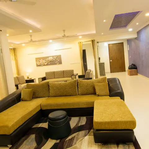 Open-plan living room with a mustard and black sectional sofa on a patterned rug, a textured purple accent wall