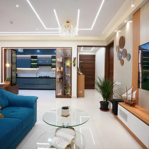 Open-plan living room with a teal sofa, a round glass coffee table, a wood-and-white TV console with decorative wall plates