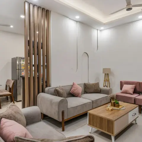 Open-plan living room with grey sofas and dusty-pink armchairs around a wood coffee table