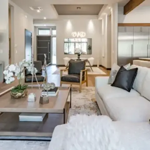 Open-plan space showing a white sectional sofa and linear fireplace in the foreground with a dining area and kitchen visible beyond