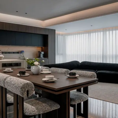 Open-plan space with a dark wood kitchen island, a bouclé-upholstered dining table setting