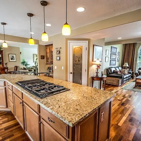 Open-plan view from a granite-topped kitchen island with pendant lights through to an adjoining dining and living area