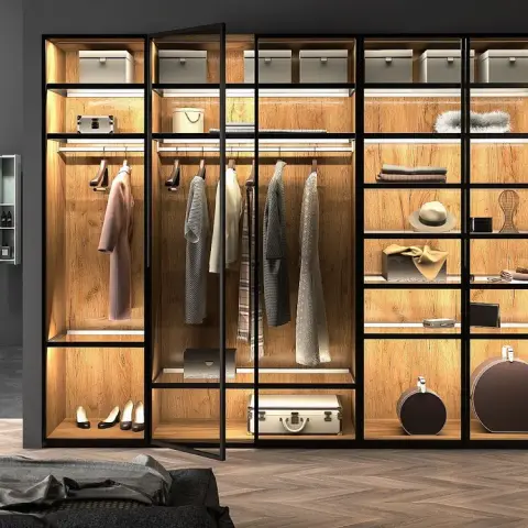 Open walk-in wardrobe in slim black steel frames with LED-lit oak-lined bays — hanging rails