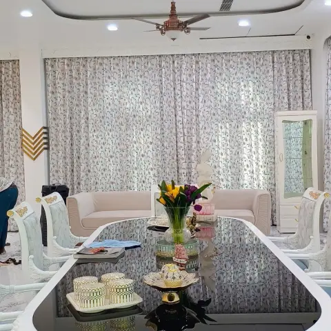 Ornate white-and-gold French-provincial dining table set beneath a crystal strand chandelier and ceiling fan