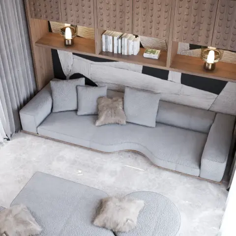 Overhead view of a long low boucle-grey floor sofa set against a carved-timber display wall with two amber glass lamps