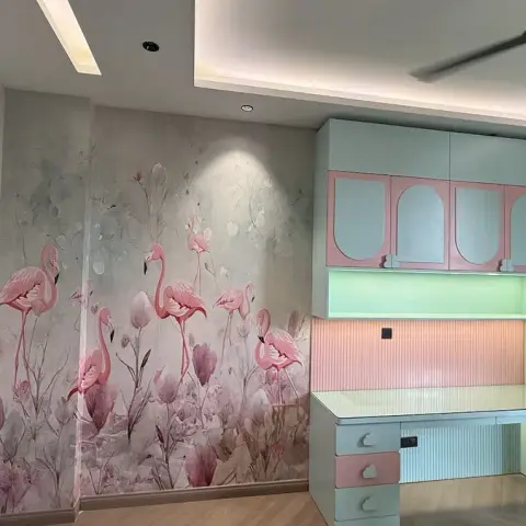 Pastel pink and mint kids' study nook with arch-shaped cabinet shutters against a flamingo mural wallpaper wall