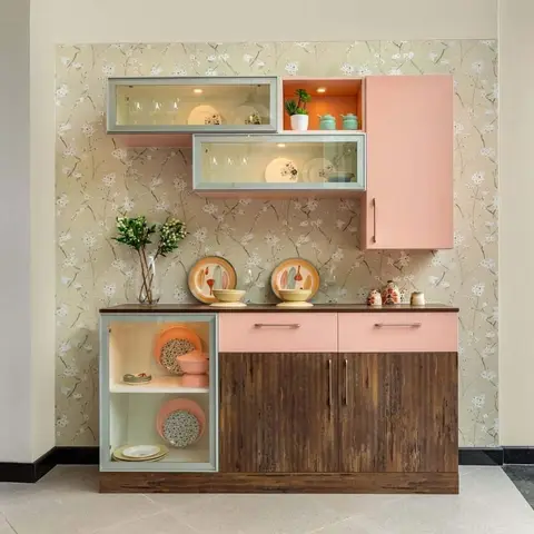 Pastel pink and mint two-tone crockery unit with glass-front display cabinets against a floral cherry-blossom wallpaper, styled with plates and a vase.
