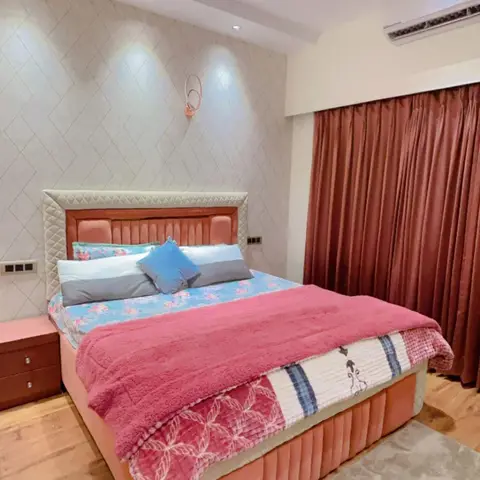 Peach channel-tufted bed inside a cream quilted headboard frame, set against a diamond-lattice textured wall lit by three ceiling washers