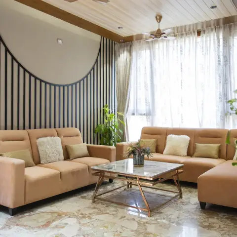 Peach velvet sofas facing a marble-top brass coffee table against a wall of slim black fins framing a big circular reveal