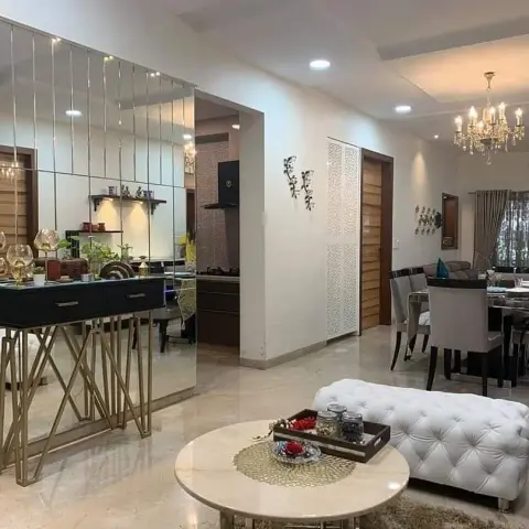 Photo across an open-plan flat: from the round marble coffee table and white tufted bench in the living zone