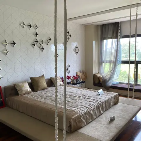 Photo of a bed suspended on fabric-sleeved ropes over an upholstered floor plinth