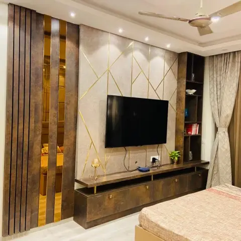 Photo of a bedroom TV wall in rust-brown laminate: vertical fluted battens with gold mirror strips at the left