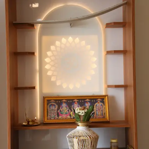 Photo of a built-in teak-laminate pooja unit with a backlit CNC lotus-and-Om panel inside an arched cove, stepped side shelves