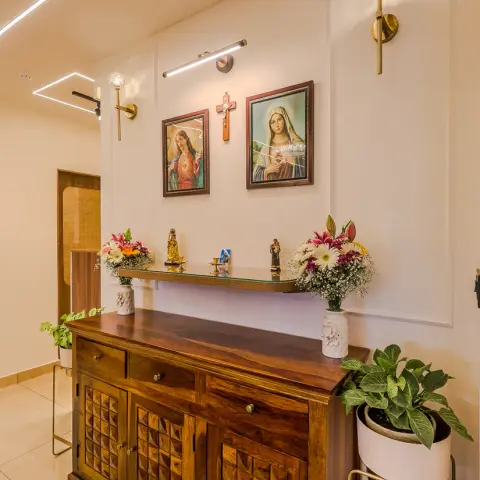 Photo of a Christian home prayer corner: framed Sacred Heart and Madonna pictures either side of a wooden crucifix under a slim picture light