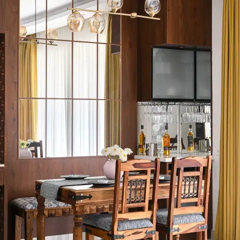 Photo of a dining corner with a carved sheesham table and iron-strapped chairs against a walnut-panelled wall