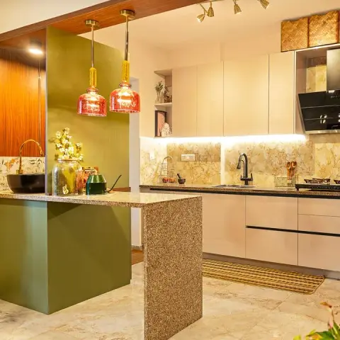 Photo of a kitchen where an olive fluted breakfast counter in speckled granite juts into the room under two red glass pendants