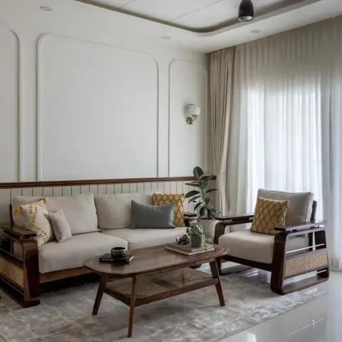 Photo of a living room from the window side: a sheesham-and-cane sofa and armchair with mustard ikat cushions