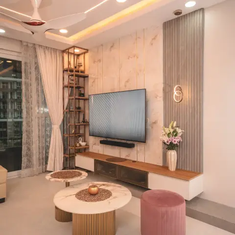 Photo of a living room with a blush marble-look TV slab inlaid with brass lines, a grey fluted panel carrying a gold double-ring pendant