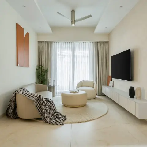 Photograph of a compact cream lounge: two curved boucle swivel chairs with a houndstooth throw, a round leather ottoman on a circular carved rug